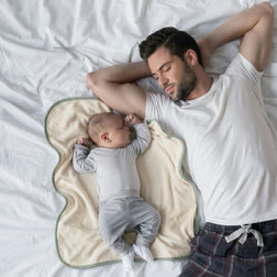 A baby asleep on the Lillypad next to a sleeping father